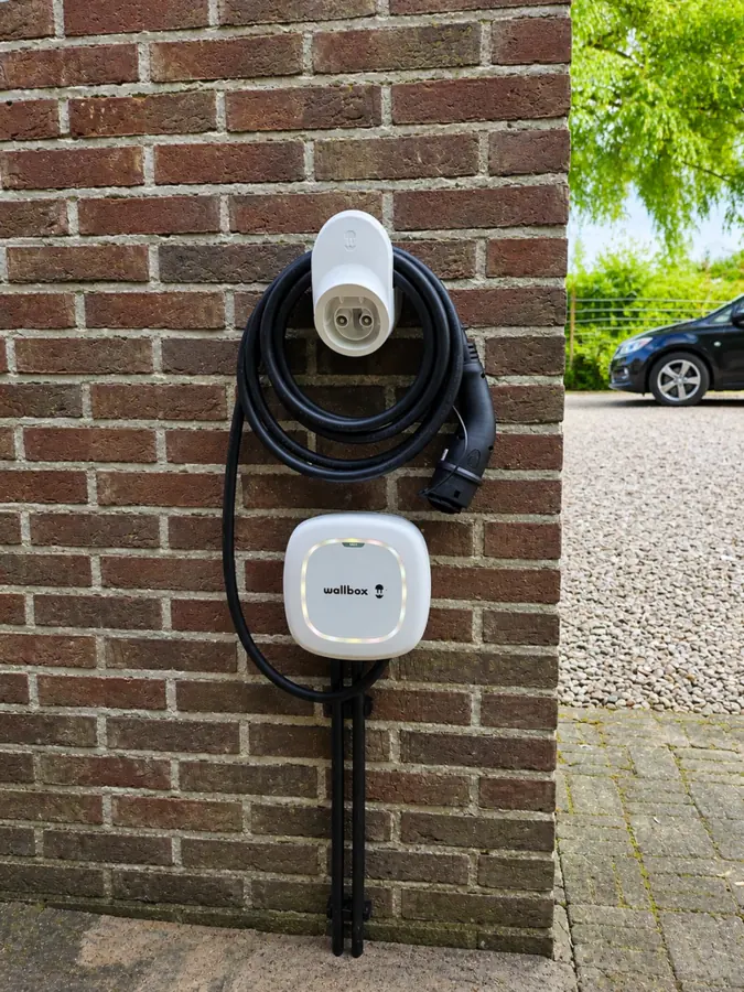 Laadpaal aan een gevel met laadkabel, geplaatst door DoeHetSolar